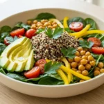 Fresh spinach salad with avocado, quinoa, cherry tomatoes and roasted chickpeas.
